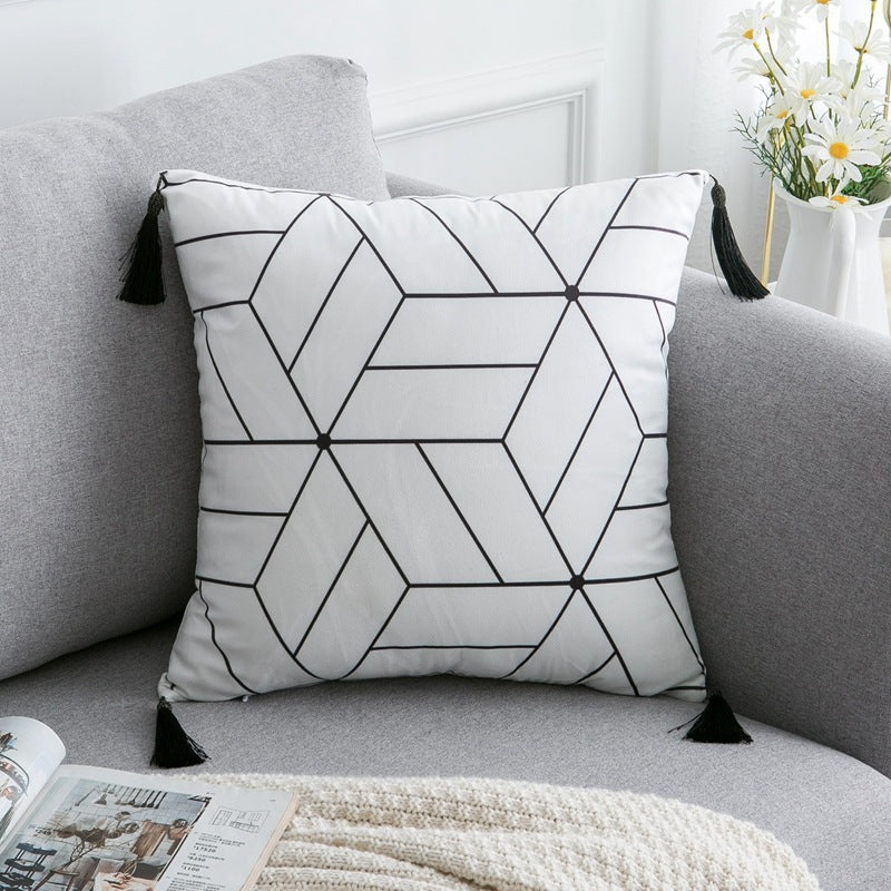 Housse de coussin en polyester satiné Nesty - Motif de losanges au trait noir, coins à glands, sur un canapé gris