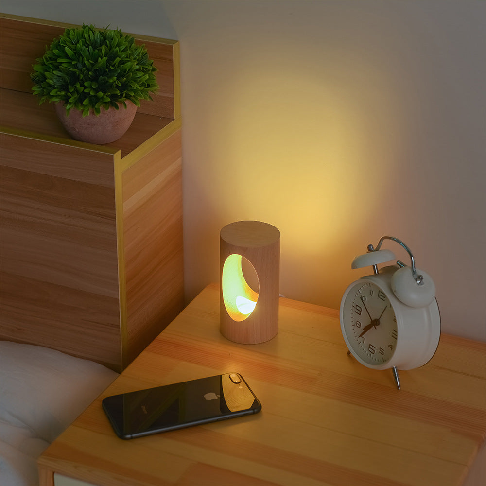 Lampe de lecture LED en bois massif Nesty - Sur une table de chevet avec réveil et smartphone