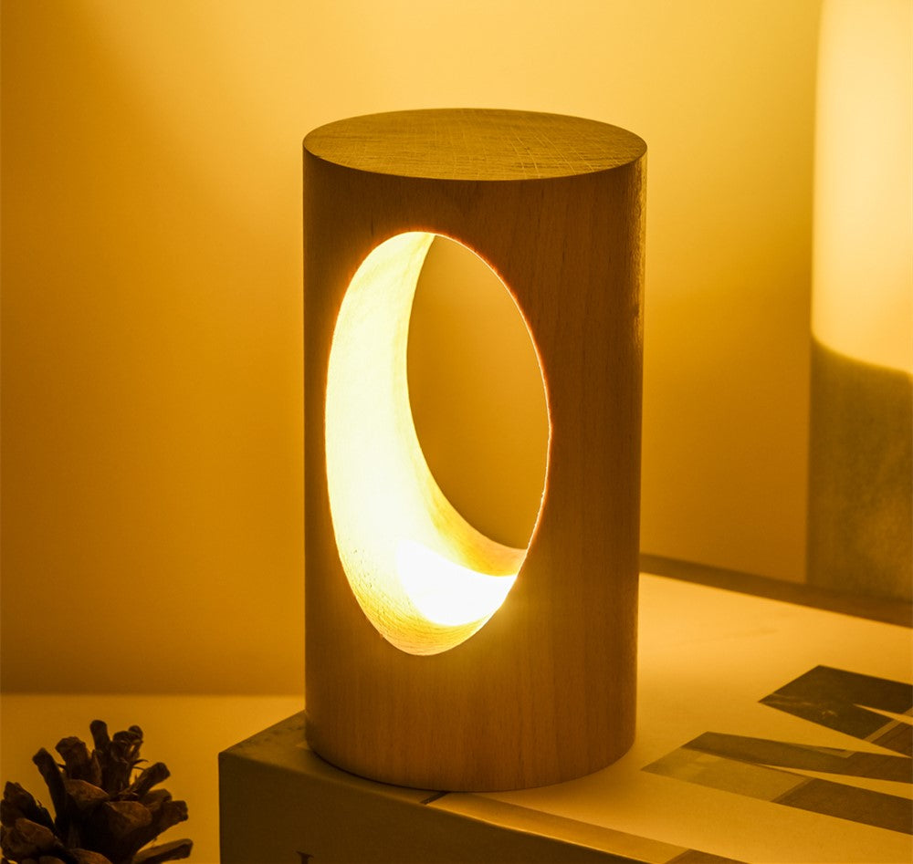 Lampe de lecture LED en bois massif Nesty - Découpe en croissant de lune, posée près de pommes de pin