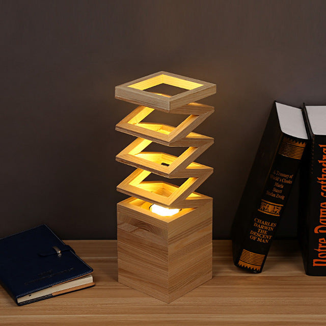 Lampe à poser créative en bois massif Nesty - Modèle à losanges empilés, posée près de livres