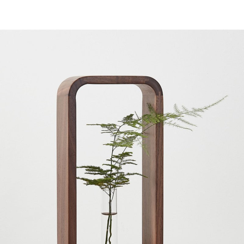 Vase soliflore en bois et verre Nesty - Gros plan du cadre en noyer et du tube en verre avec une branche d'asparagus