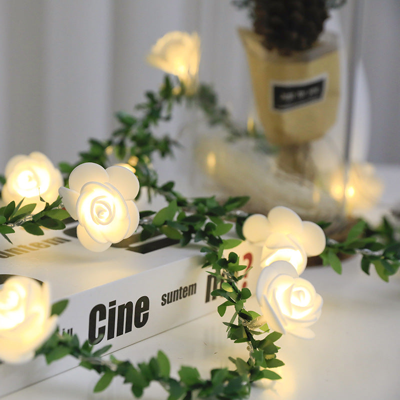 Guirlande lumineuse LED roses et lierre Nesty - Roses blanches allumées et feuillage posés sur des livres