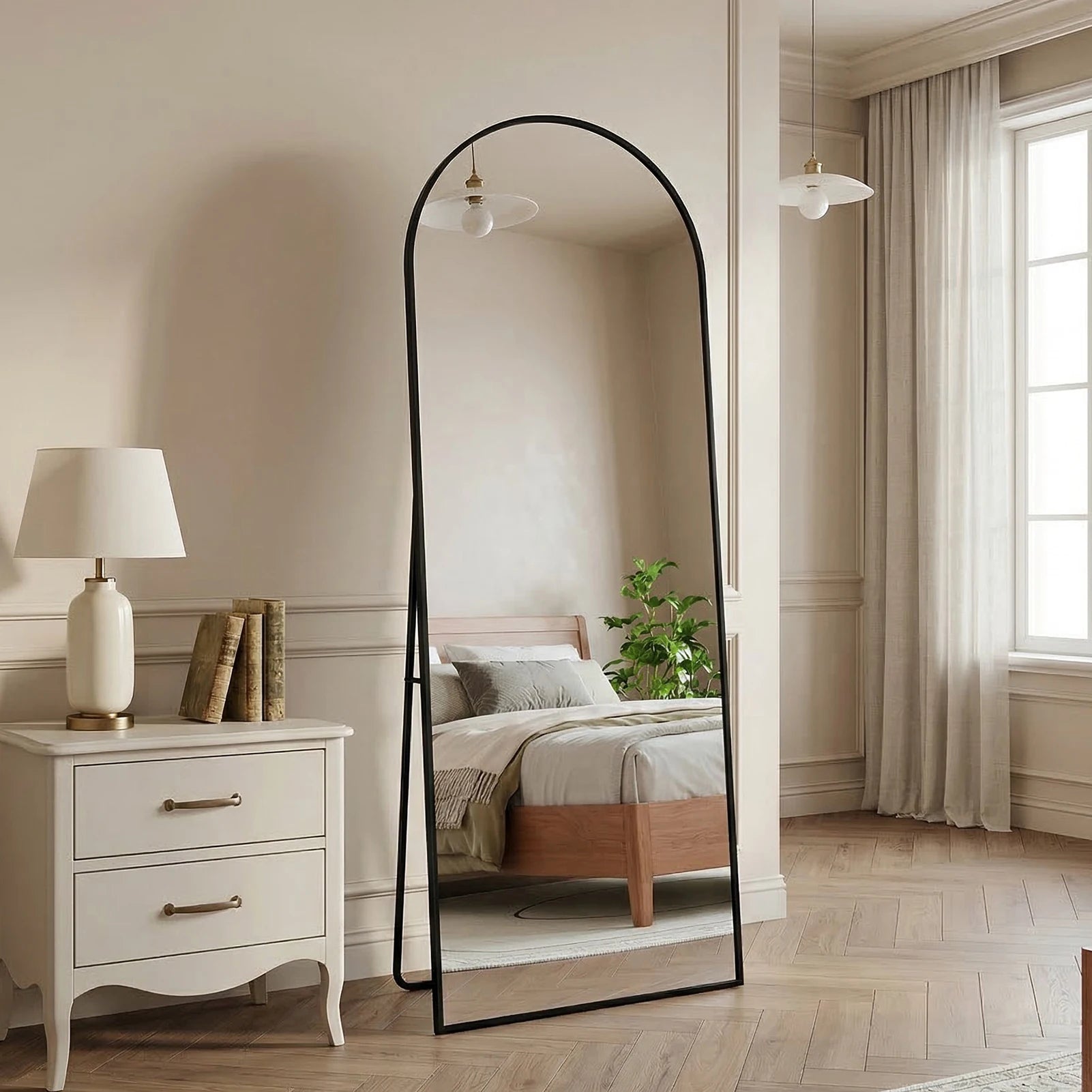Miroir sur pied cintré noir Nesty - Support intégré, miroir cintré noir sur pied dans une chambre beige, près d'une table de chevet blanche avec lampe et livres