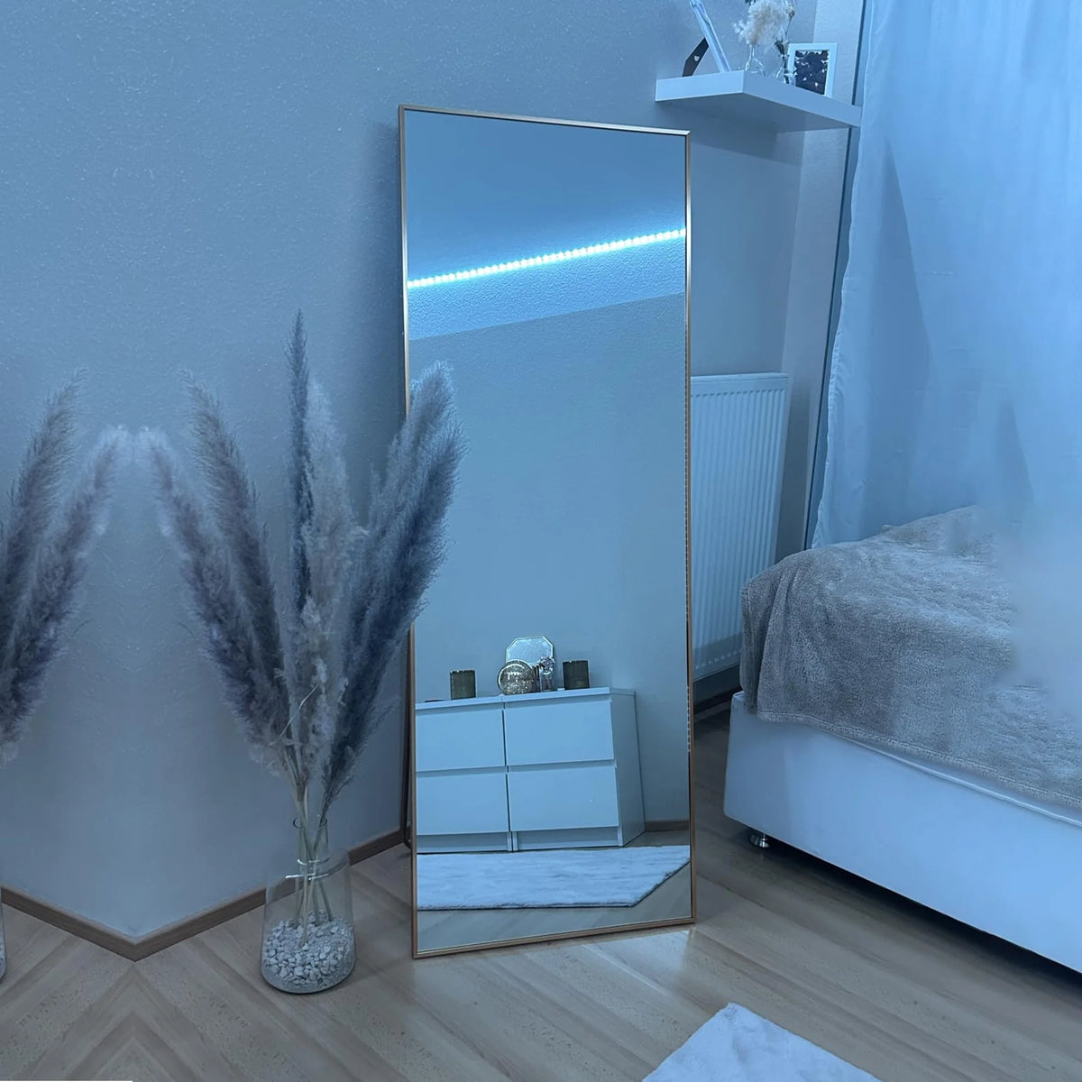 Miroir psyché doré Nesty - Modèle 150 x 40 cm avec ruban LED bleu allumé, posé au sol dans une chambre