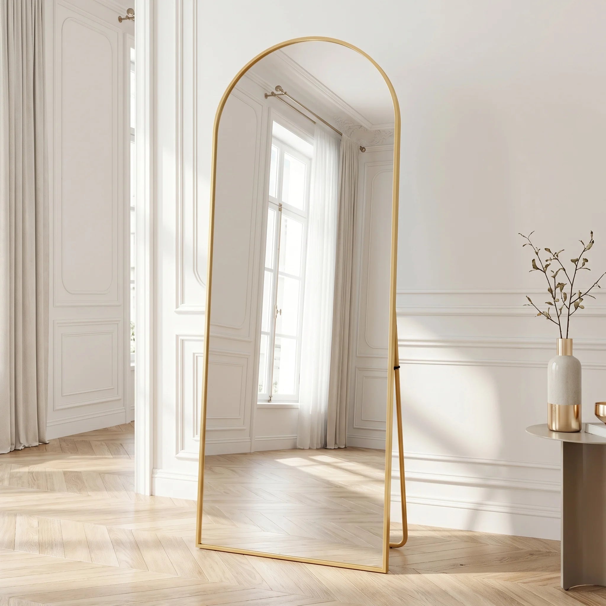 Miroir psyché cintré doré Nesty - Sur pied, miroir psyché cintré doré sur pied dans une chambre habillée de boiseries blanches, près d'un rideau et d'une fenêtre