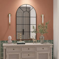 Miroir fenêtre cintré Nesty - Cadre noir rustique, miroir fenêtre cintré cadre noir rustique accroché sur un mur terracotta, au-dessus d'une commode blanche avec accessoires dorés