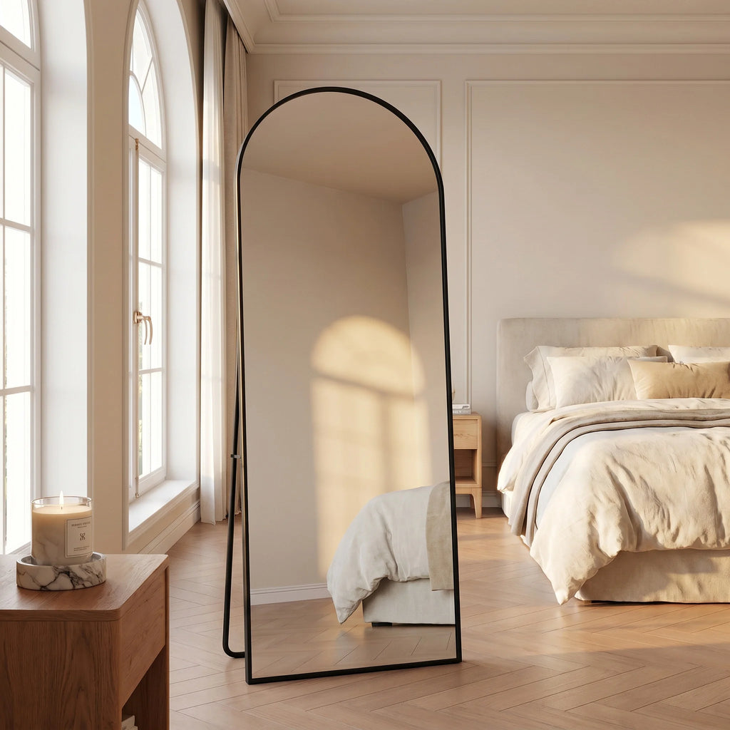 Miroir psyché cintré Nesty - Cadre noir en chambre, reflet d'une fenêtre en arche et d'un lit aux draps beiges