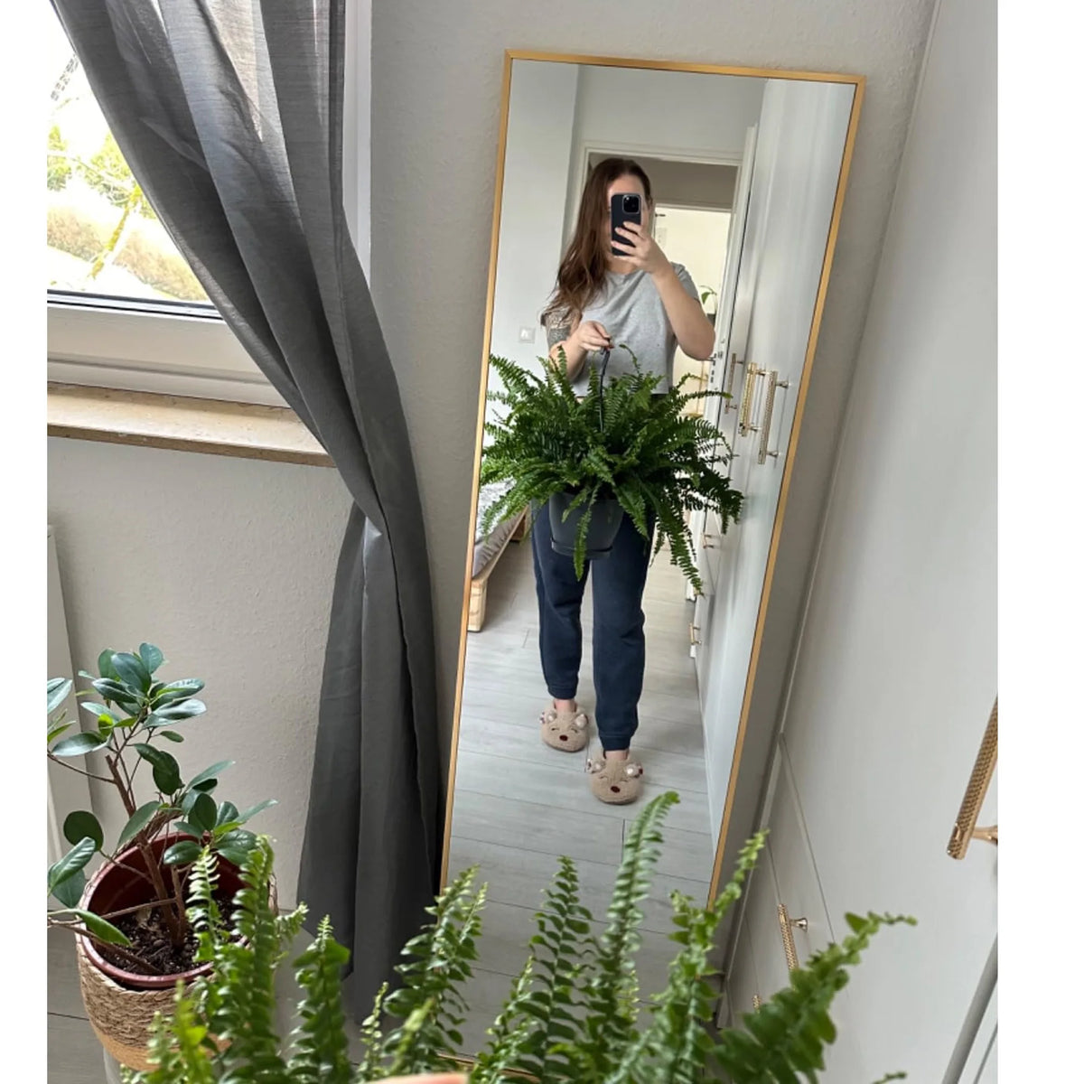 Miroir psyché doré Nesty - Reflet d'une femme prenant un selfie avec une fougère, cadre doré
