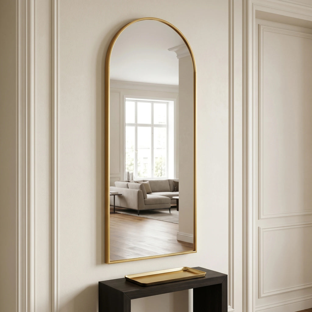 Miroir psyché cintré doré Nesty - Sur pied, accroché au mur au-dessus d'une console noire avec plateau doré, dans une entrée aux boiseries blanches