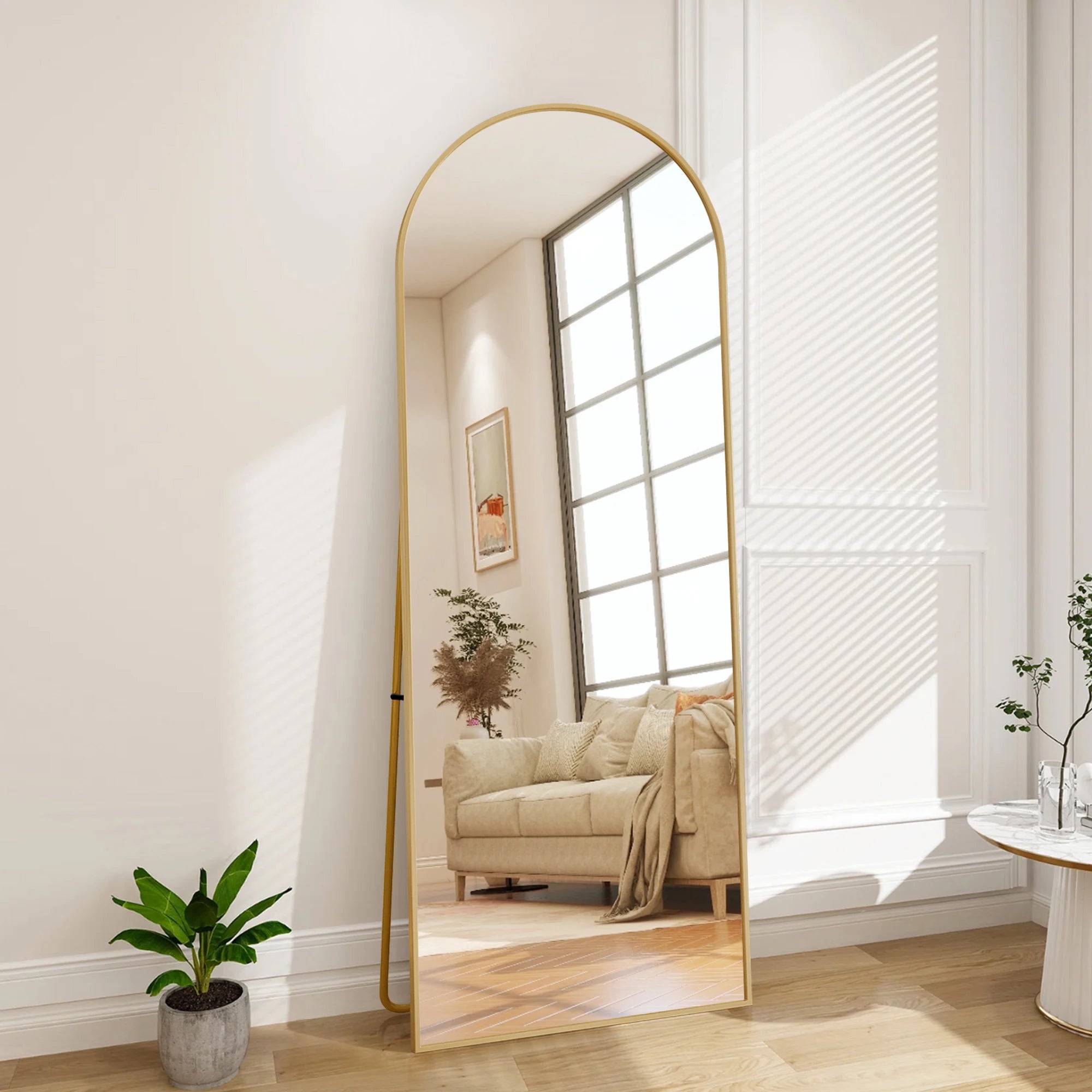 Miroir psyché doré Nesty - Posé au sol dans un salon, reflet d'une fenêtre, d'un tableau et d'une plante