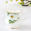 Pot à lait en porcelaine fine, style européen, 170ml Nesty, motif floral peint et liseré doré, sur table blanche avec branches en fond