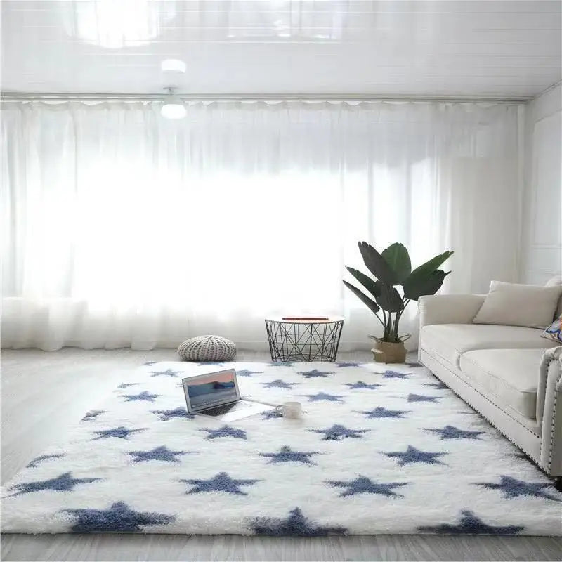 Tapis blanc à motifs d'étoiles bleu marine, posé au sol dans un salon devant un canapé clair et une plante verte.