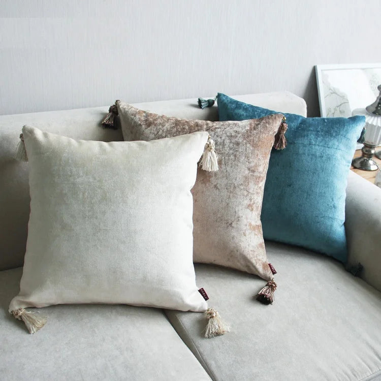 Housse de coussin en coton et lin, broderie pissenlit Nesty, quatre housses de coussin en velours uni à pompons, coloris écru, taupe et bleu canard, posées sur canapé gris clair