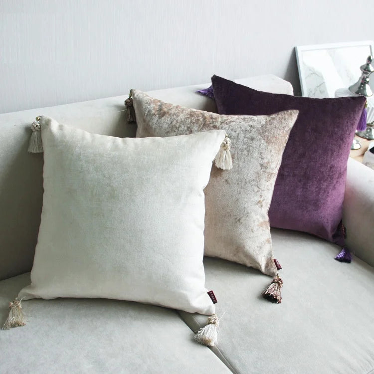 Housse de coussin en coton et lin, broderie pissenlit Nesty, quatre housses de coussin en velours uni à pompons, coloris écru, taupe et violet, posées sur canapé gris clair