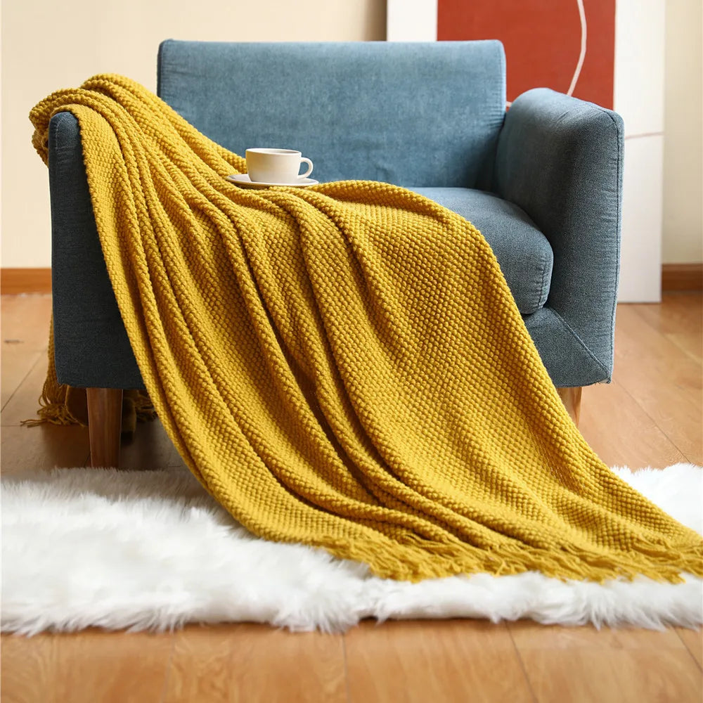Plaid en maille chunky à franges, tricot épais pour canapé Nesty, plaid en maille chunky jaune moutarde à franges, drapé sur fauteuil bleu avec tasse de café, sur tapis en fausse fourrure blanche