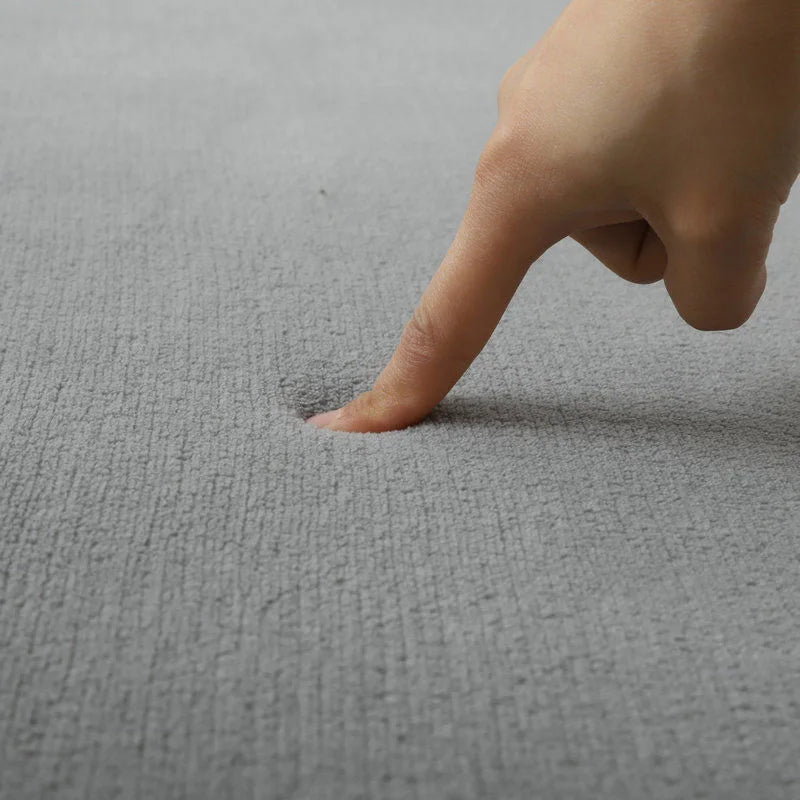 Tapis en velours corail uni Nesty - Plusieurs coloris, coloris gris avec un doigt enfoncé dans le velours moelleux