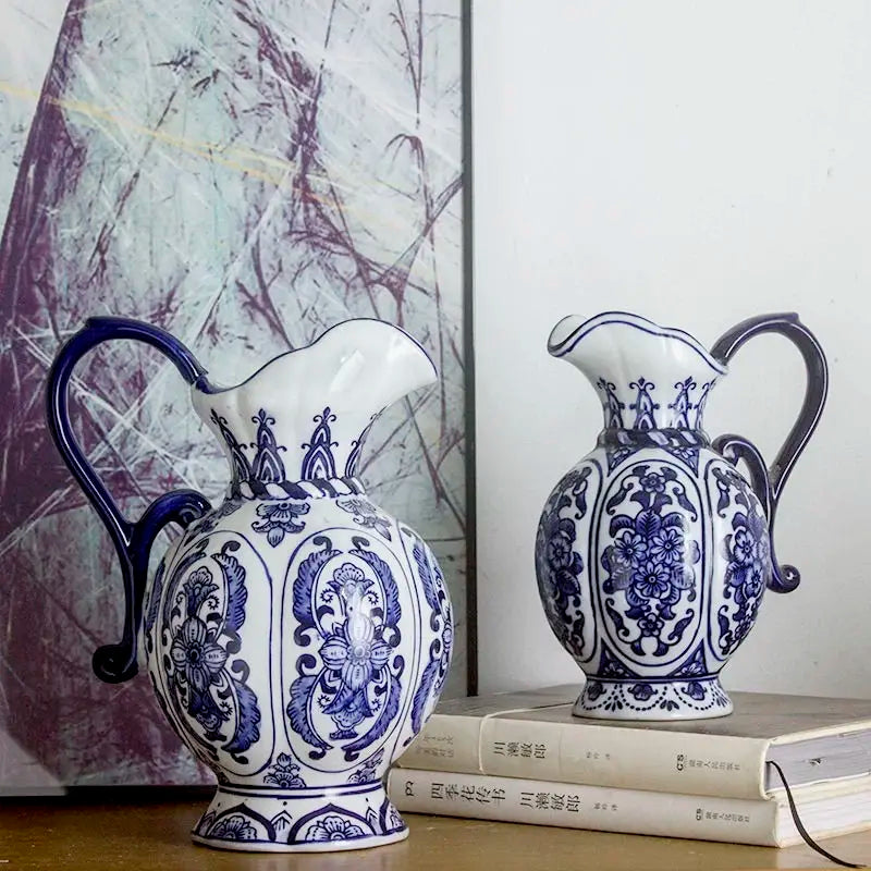Vase en porcelaine bleu et blanc, motif ancien Nesty, deux pichets à motifs floraux et anse assortie, posés devant un tableau abstrait