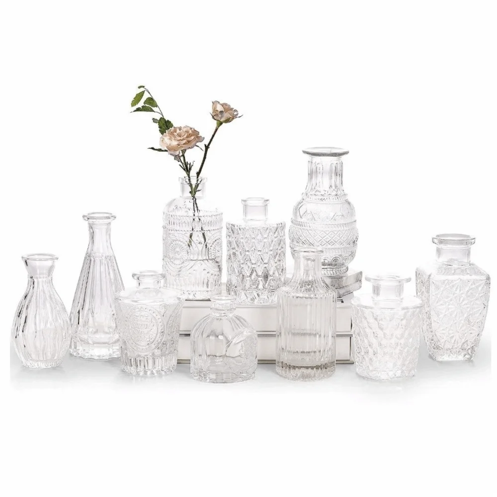 Set de mini vases en verre transparent, motif en relief - Nesty - Douze mini vases en verre transparent de formes variées disposés en groupe, l'un garni de roses roses pâles