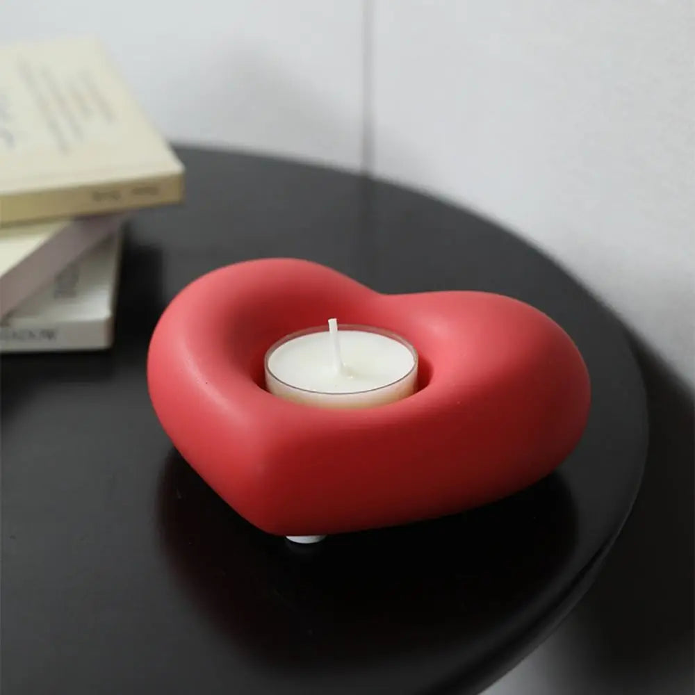 Bougeoir coeur en céramique Nesty - Modèle rouge mat avec bougie chauffe-plat allumée, sur table noire près de livres