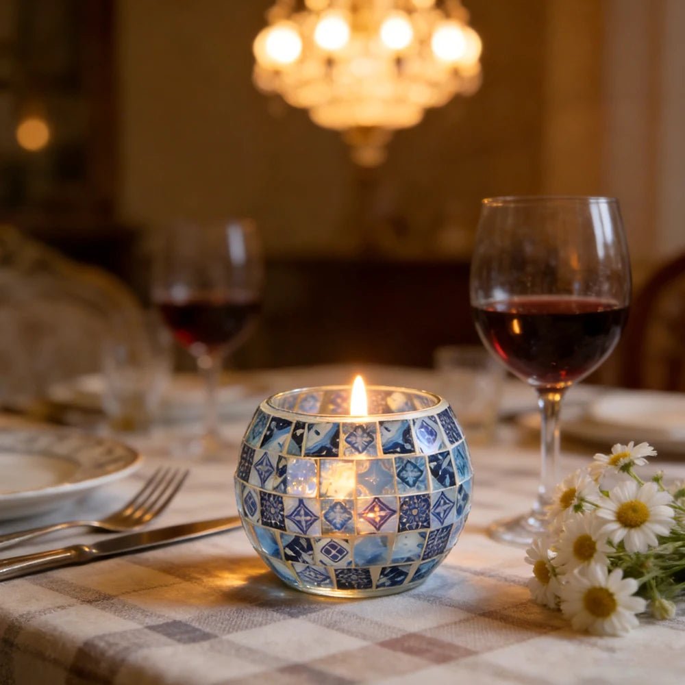 Photophore en verre mosaïque bleu et blanc, bougie allumée sur table dressée avec verres à vin et marguerites - Nesty