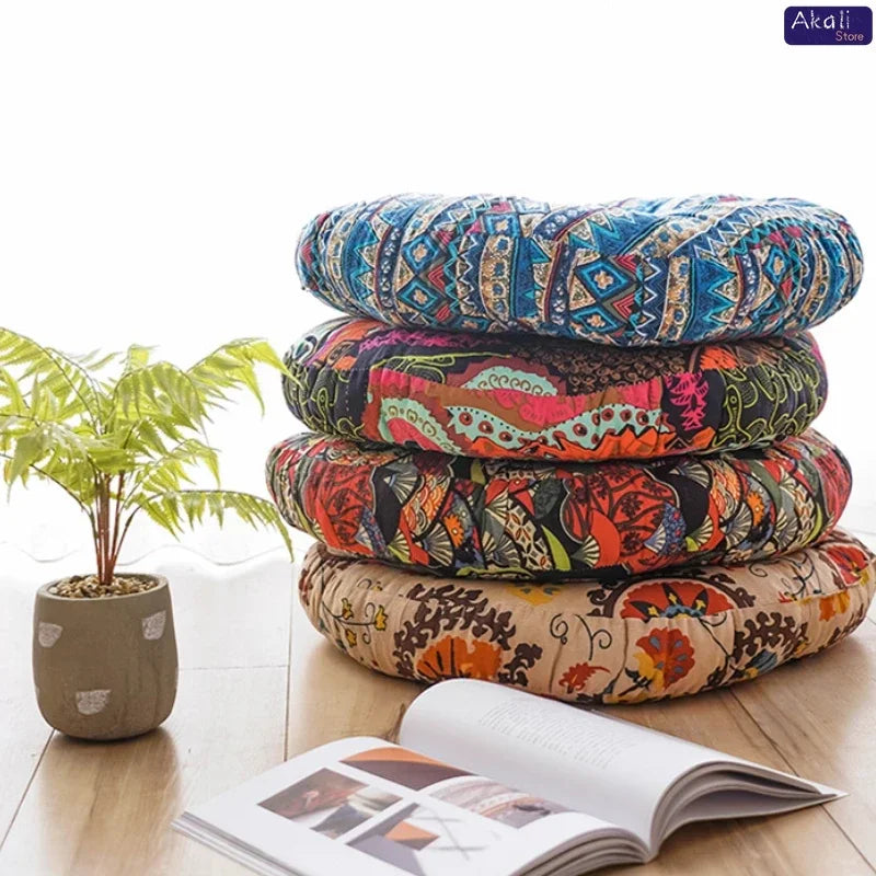 Coussin de sol rond en coton et lin, esprit bohème, tatami Nesty, quatre coussins de sol ronds empilés à imprimés folkloriques (aztèque bleu, floral multicolore, feuillage rouge, floral beige), près d'une plante et d'un livre ouvert