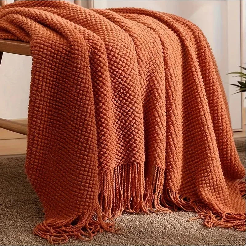 Plaid tricoté terracotta Nesty - Drapé sur banc en bois, franges tombées au sol sur tapis