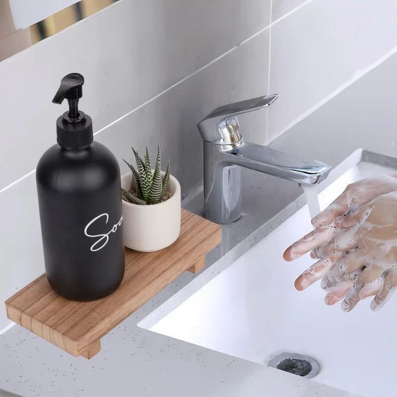 Piédestal en bois Nesty - Présentoir pour savon ou bougie, posé au bord d'un lavabo de salle de bain avec un flacon de savon noir et une plante grasse, robinet ouvert