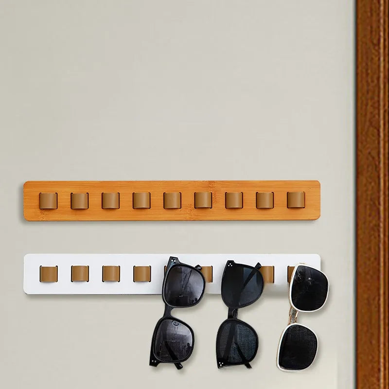 Porte-lunettes mural en bois Nesty, deux coloris montés sur un mur beige, plusieurs paires de lunettes accrochées sur la version blanche
