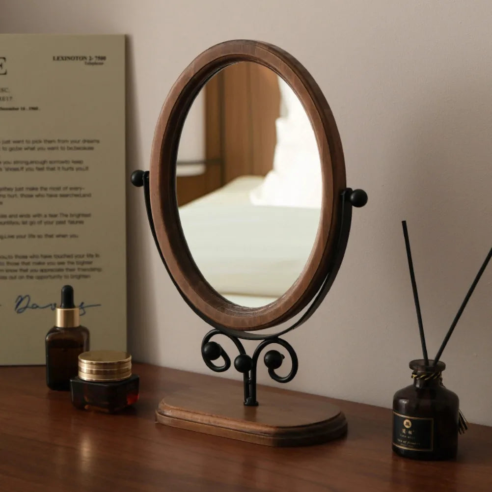 Miroir à poser ovale en bois pivotant sur pied métal noir enroulé, socle en bois, sur bureau avec flacons cosmétiques - Nesty