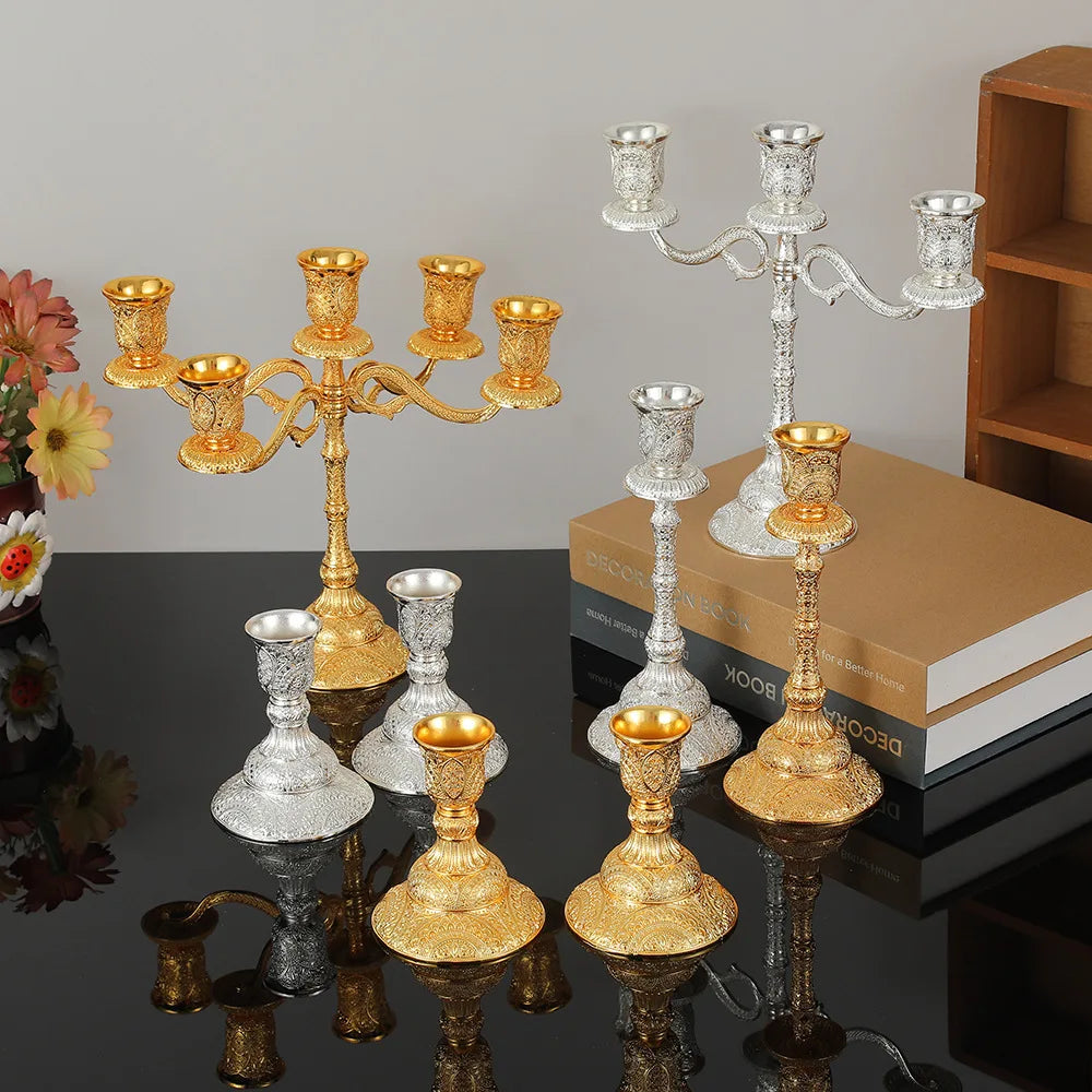 Duo de bougeoirs en métal Nesty - Collection de chandeliers et bougeoirs dorés et argentés de tailles variées, sur une table avec livres et fleurs