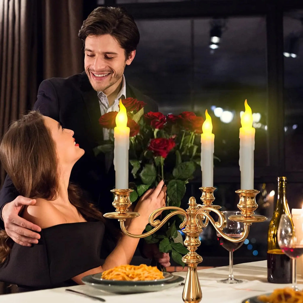 Bougies LED effilées sans flamme, lumière chaude vacillante Nesty, chandelier doré à trois branches avec bougies LED fuselées allumées, couple attablé pour un dîner romantique avec roses rouges