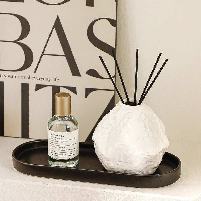 Diffuseur de parfum en céramique avec plateau Nesty - Vase blanc et flacon de parfum sur plateau noir, près d'une affiche typographique