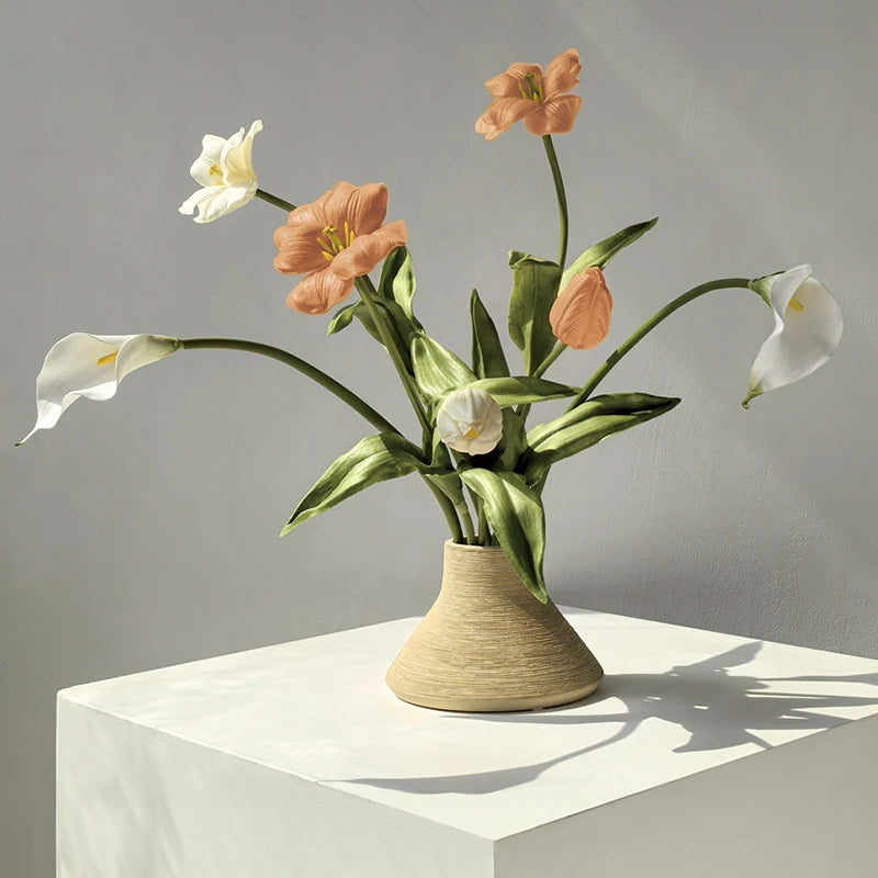 Vase en céramique papillon, texture brossée wabi-sabi Nesty, la forme beige conique garnie d'un bouquet de tulipes et calla pêche et blanches, sur socle blanc