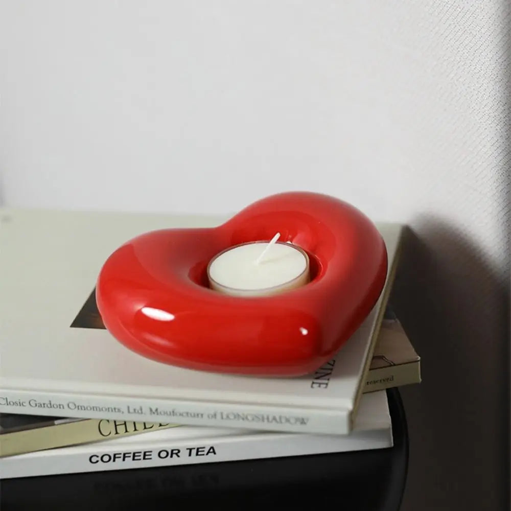 Bougeoir coeur en céramique Nesty - Modèle rouge brillant avec bougie chauffe-plat, posé sur une pile de livres