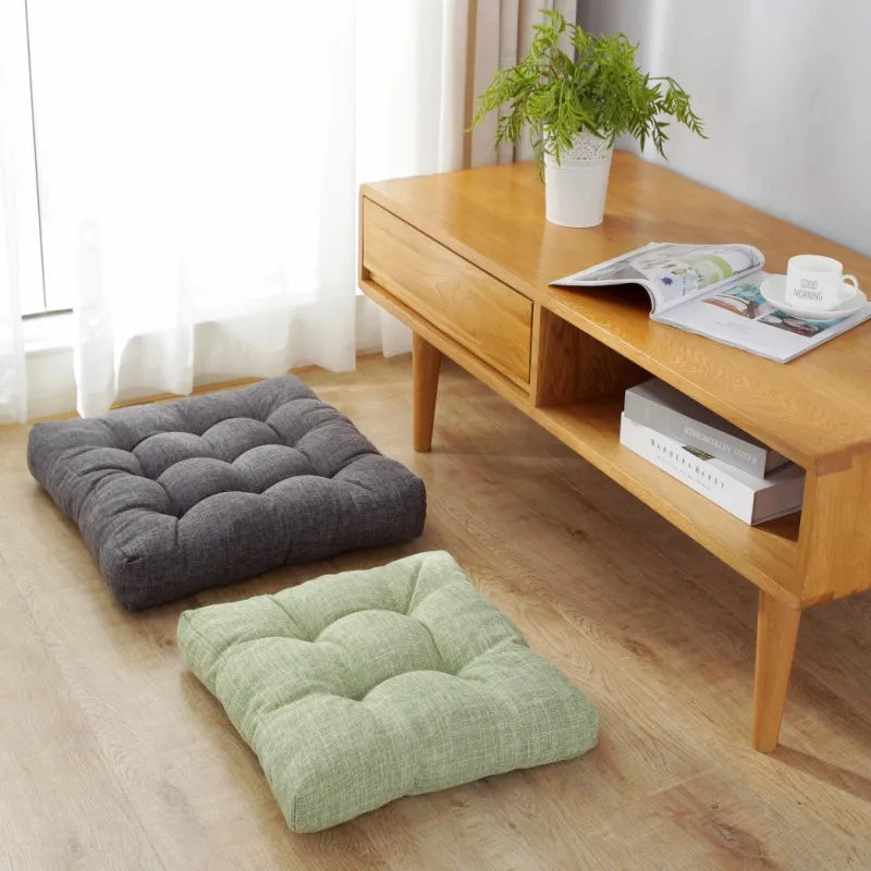 Grand coussin de sol carré tufté en lin, esprit futon, épais Nesty, deux coussins de sol carrés capitonnés, gris anthracite et vert sauge, posés au sol devant une console en bois avec plante