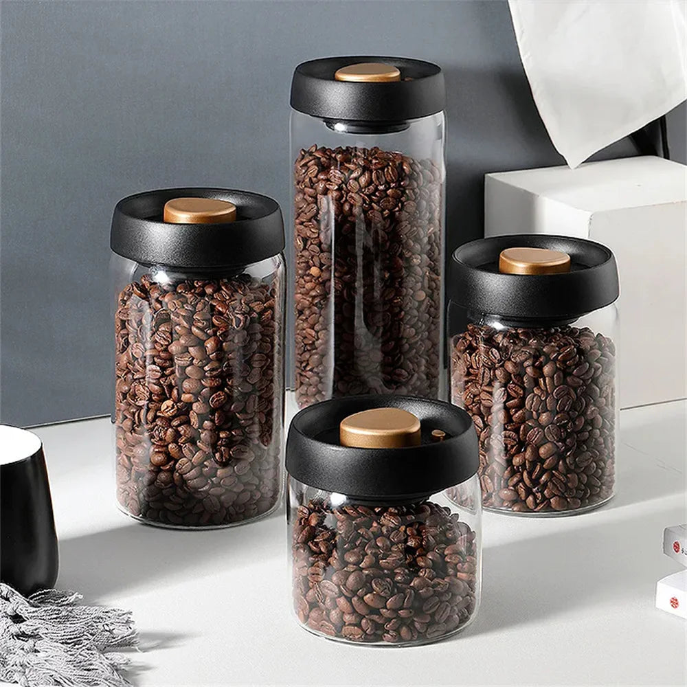Boîte hermétique en verre pour café en grains Nesty, quatre boîtes hermétiques en verre remplies de grains de café, couvercle noir à bouton doré, de tailles différentes, sur plan de travail
