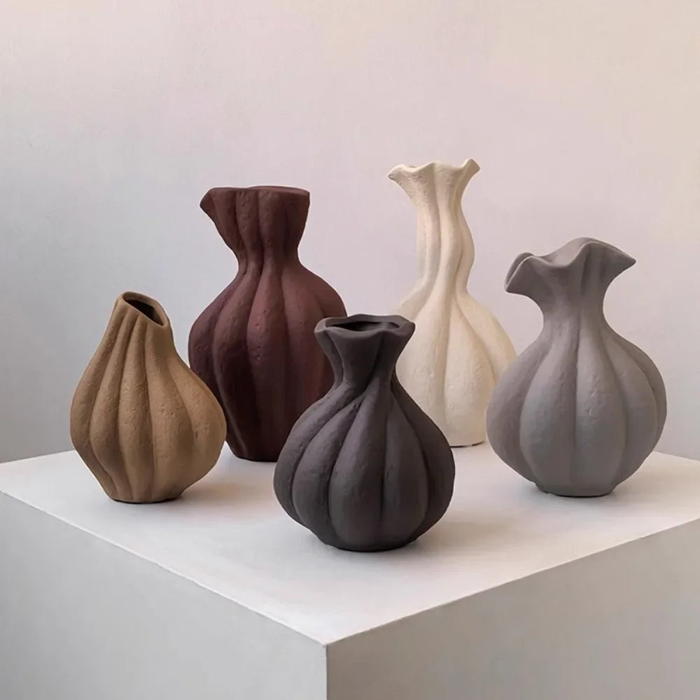 Vase en céramique irrégulier, esprit wabi-sabi, fait main Nesty, cinq formes cannelées de coloris différents, camel, bordeaux, blanc cassé, gris foncé et gris clair, sur socle blanc