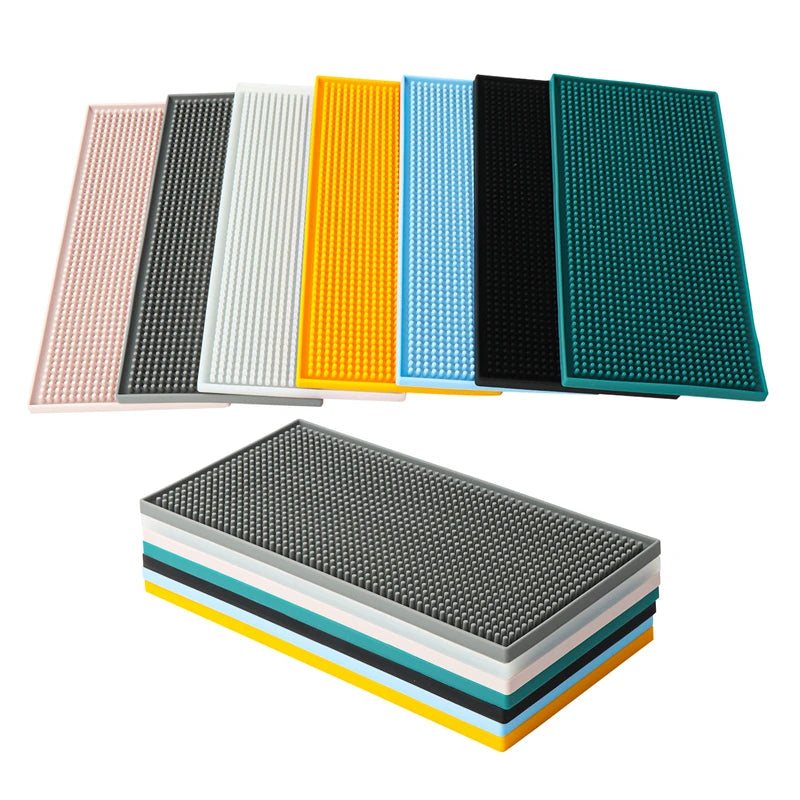 Tapis de bar en silicone épais, sept coloris (rose, gris, blanc, jaune, bleu, noir, vert canard), empilés et à plat sur fond blanc - Nesty