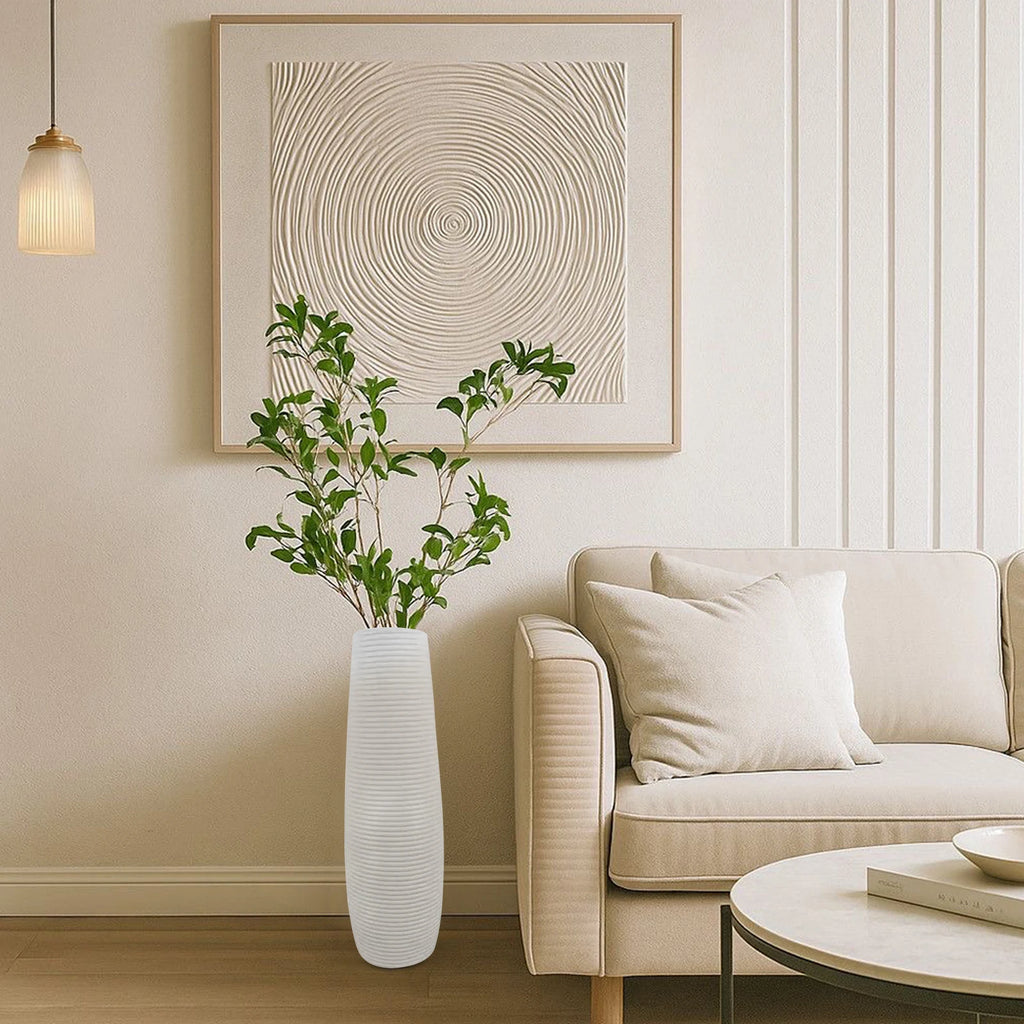 Vase décoratif à lignes texturées Nesty - Modèle blanc avec feuillage vert, sous un tableau mural, près d'un canapé beige