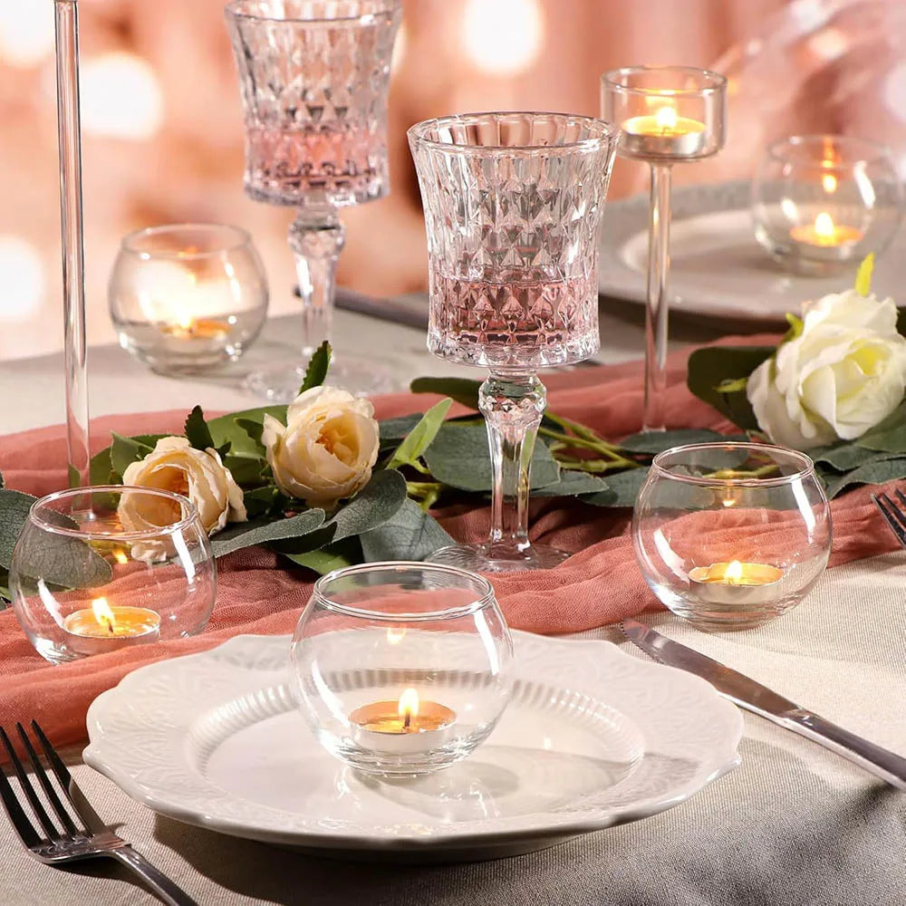 Photophores votifs en verre Nesty - Table de mariage avec verres à pied facettés roses et transparents, photophores ronds allumés et fleurs blanches
