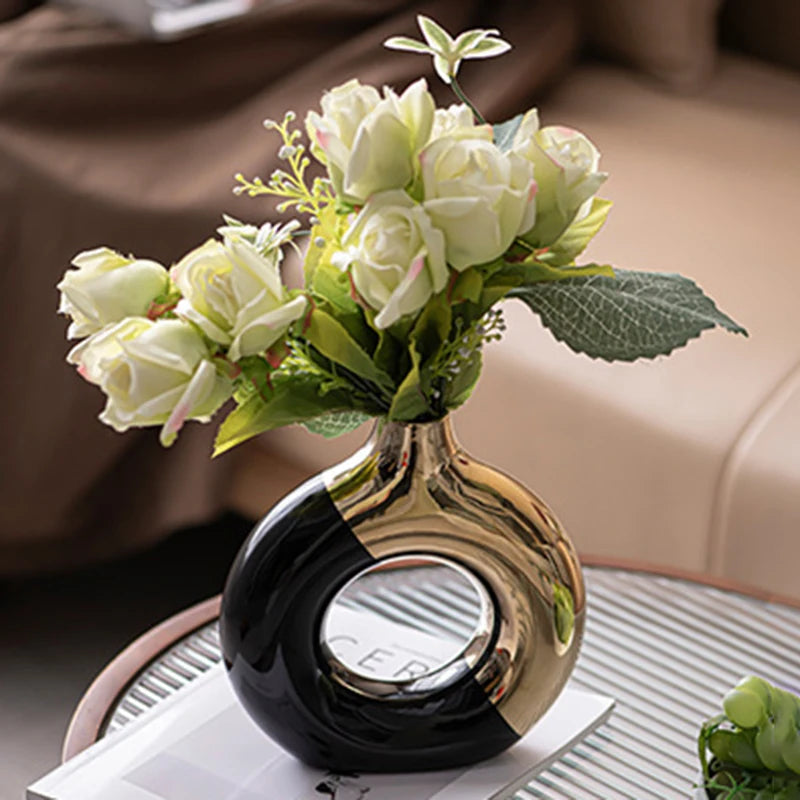 Vase en céramique doré, silhouette nordique, plusieurs tailles Nesty, vase rond ajouré bicolore noir et doré garni de roses blanches sur un plateau en verre