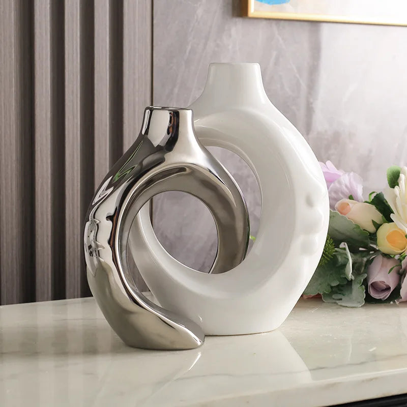 Vase en poterie Nesty - Coloris argenté et blanc entrelacés, près d'un cadre et de fleurs mauves