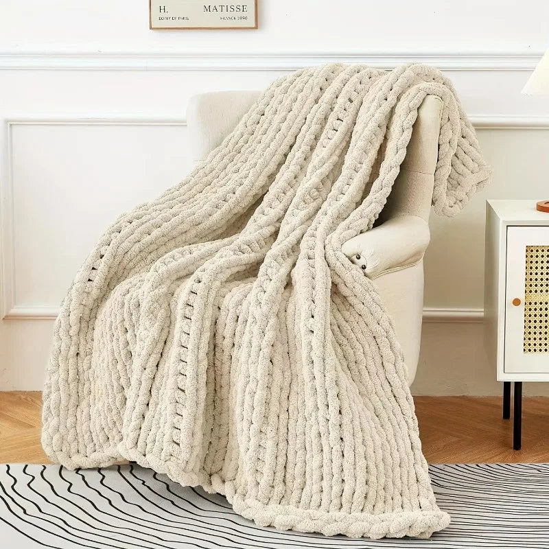 Plaid tricoté chunky knit Nesty - Drapé sur fauteuil beige, grosses mailles côtelées, dans salon lumineux