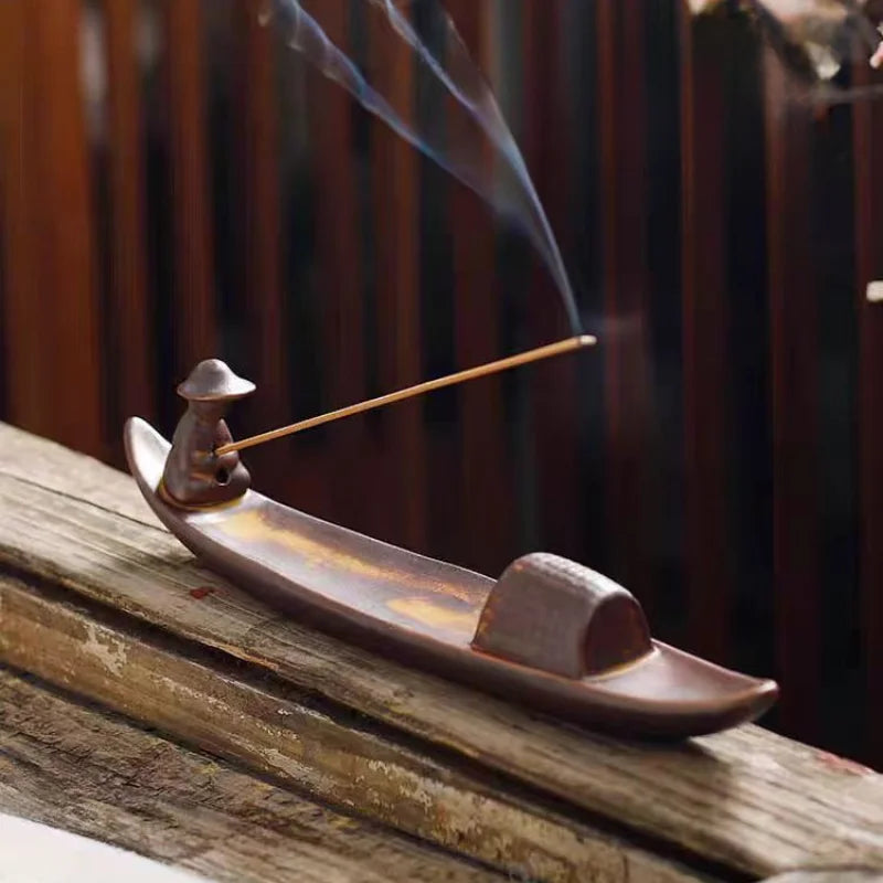 Plateau brûle-encens en céramique Nesty - Forme de barque avec figurine de pêcheur, bâtonnet d'encens allumé sur rambarde en bois