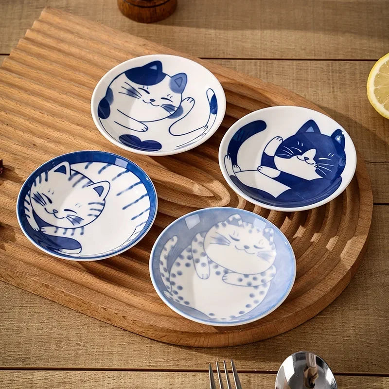 Coupelles en céramique à motif chat porte-bonheur Nesty, quatre coupelles rondes à motifs de chats bleu et blanc, posées sur une planche en bois avec citron