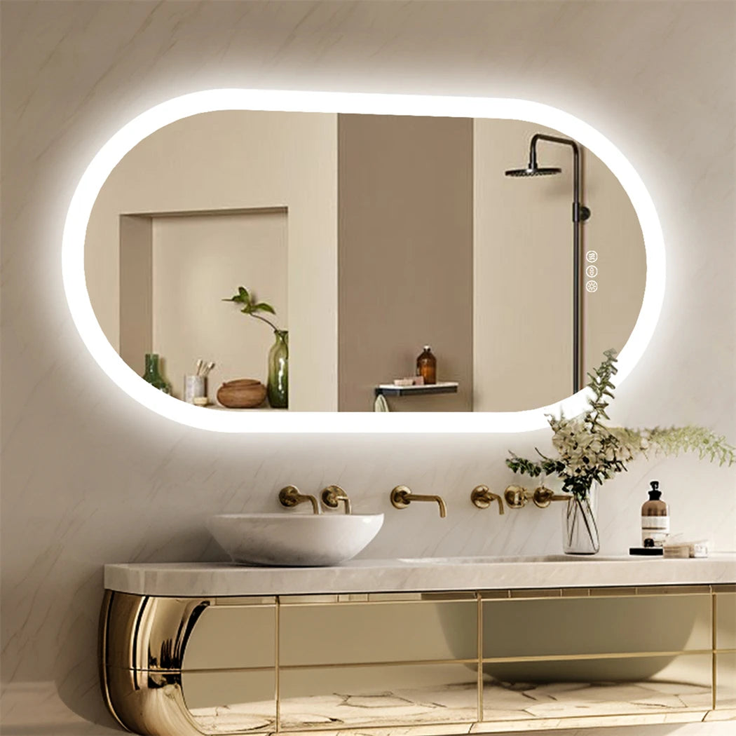 Miroir de salle de bain ovale LED Nesty - Allumé au-dessus d'un lavabo en marbre, meuble doré et douche en reflet