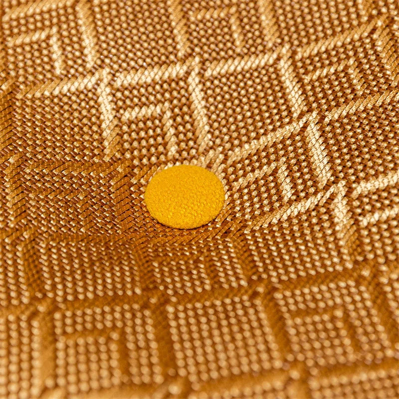 Coussin de sol rond en lin, esprit tatami, pour méditation Nesty, gros plan sur la texture tressée dorée en losanges et le bouton central jaune d'une galette de sol