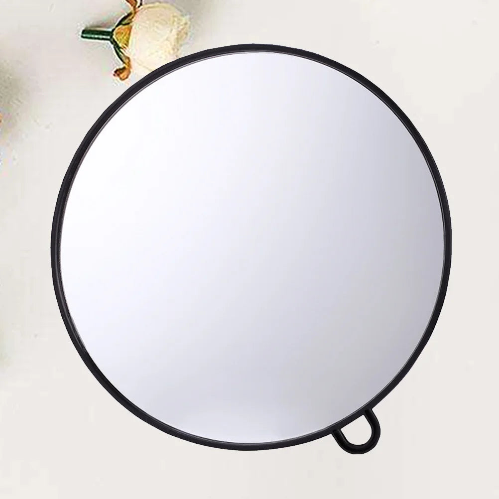 Miroir rond suspendu Nesty - Cadre noir sur fond crème avec une fleur en reflet, anneau d'accroche visible