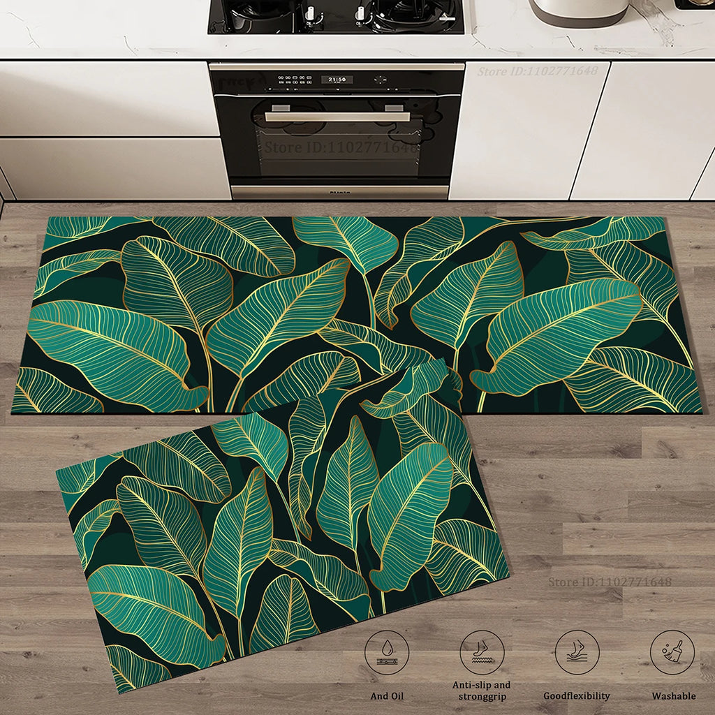 Deux tapis de cuisine assortis à motif de feuilles aux contours dorés sur fond noir et vert foncé, posés dans une cuisine.