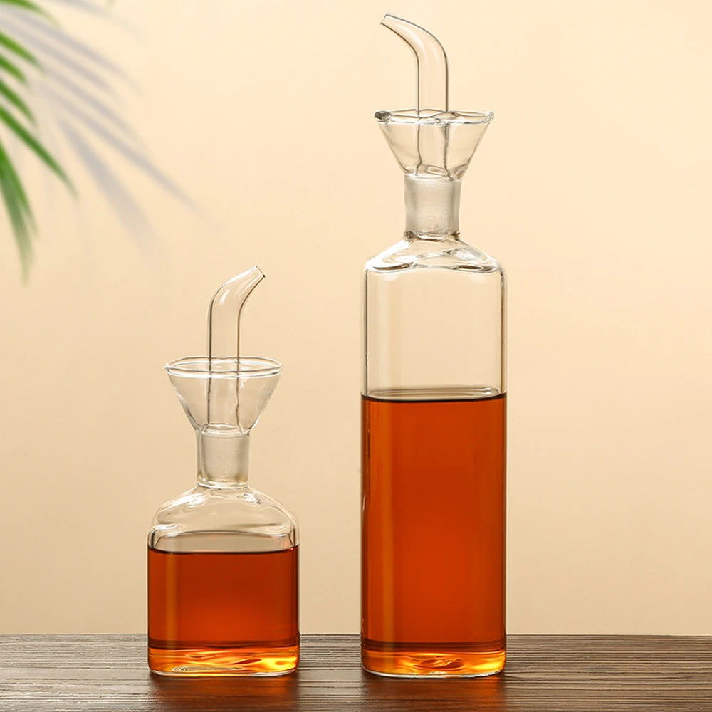 Burette à huile d'olive en verre borosilicate, anti-goutte Nesty, deux burettes en verre de tailles différentes avec bec verseur, l'une remplie d'huile ambrée et l'autre de sauce foncée, sur table en bois
